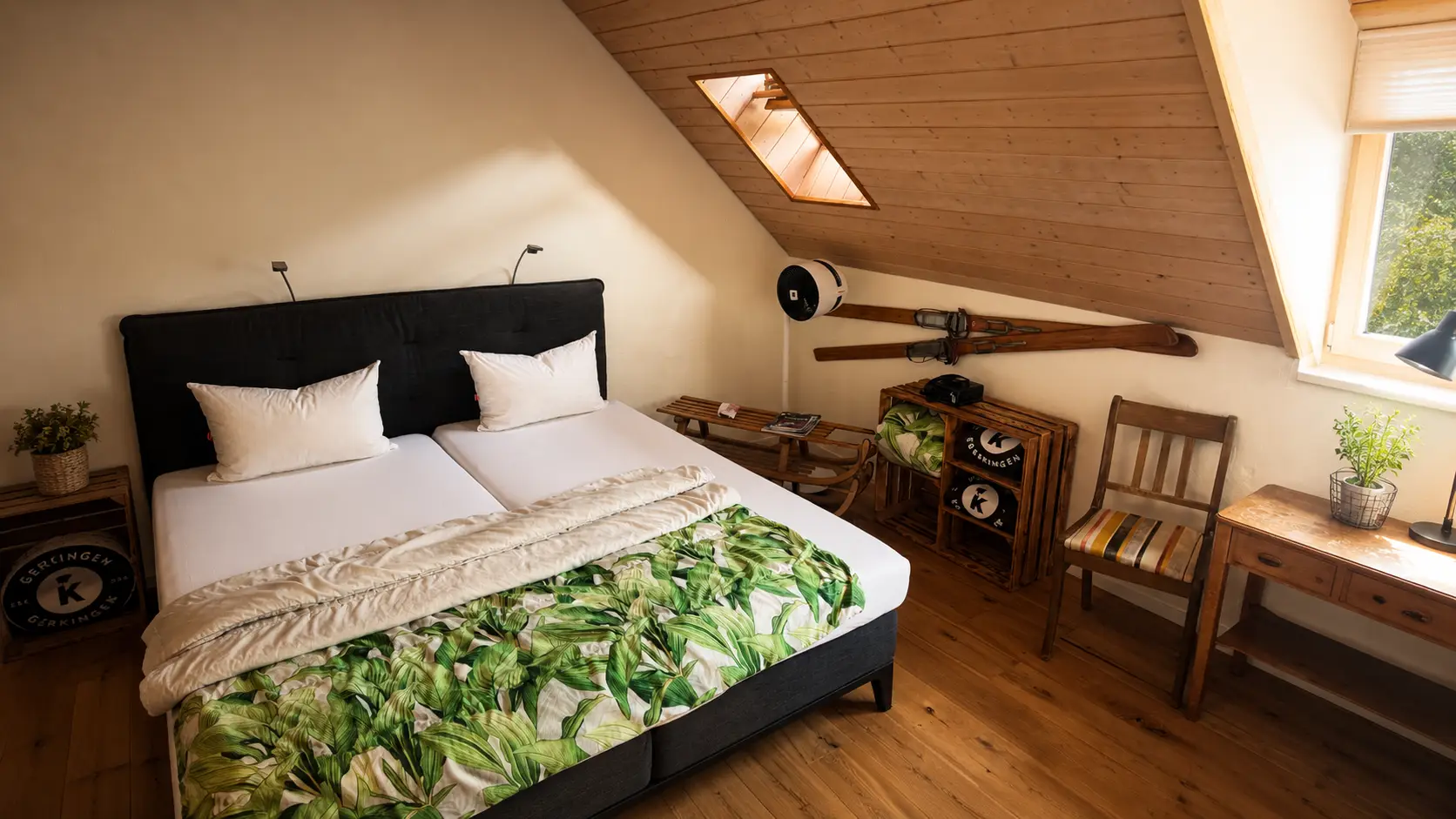 Dachzimmer im Hotel Gasthof Kreuz Egerkingen mit Doppelbett unter Holzschraege, Dachfenster, Stuhl und rustikaler Dekoration