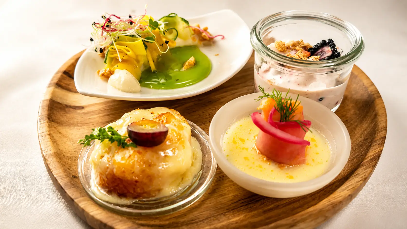 Vorspeisen-Variation auf dem Holzbrett mit Salat, Gratin, Lachsröllchen und Beeren im Glas – Gasthof Kreuz Egerkingen