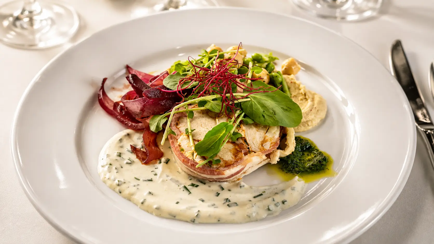 Medaillon im Speckmantel mit Kräuterrahmsauce, Radicchio und Pesto auf weissem Teller – Gasthof Kreuz Egerkingen